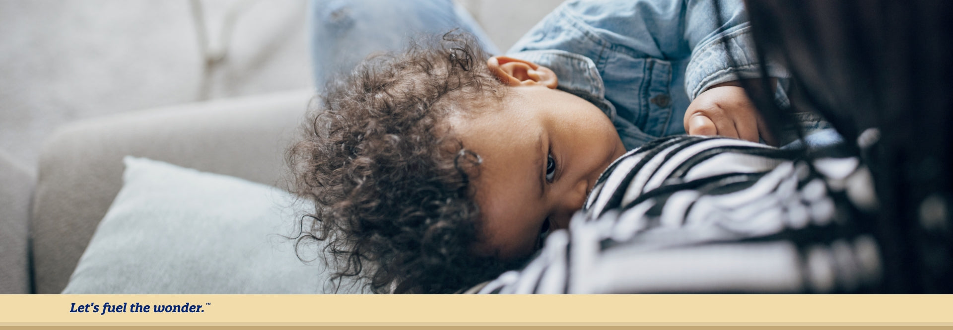 Baby breastfeeding from parent's nipple while baby is laying down on their right side looking up at breastfeeding parent