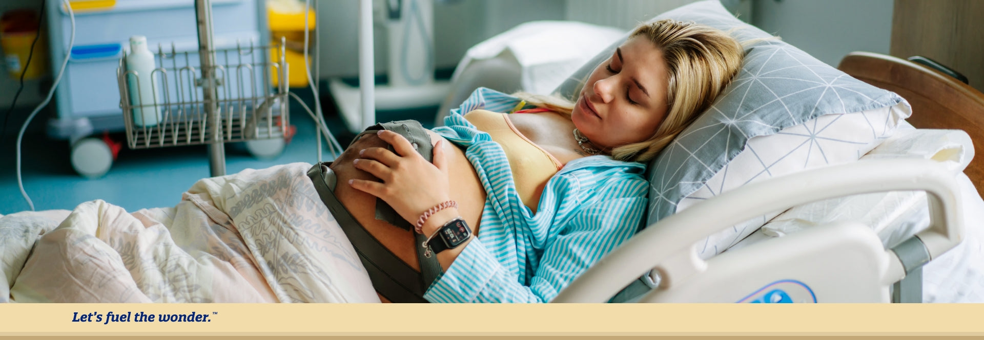 Pregnant woman with laying in hospital bed with their eyes closed and their left hand on pregnant belly